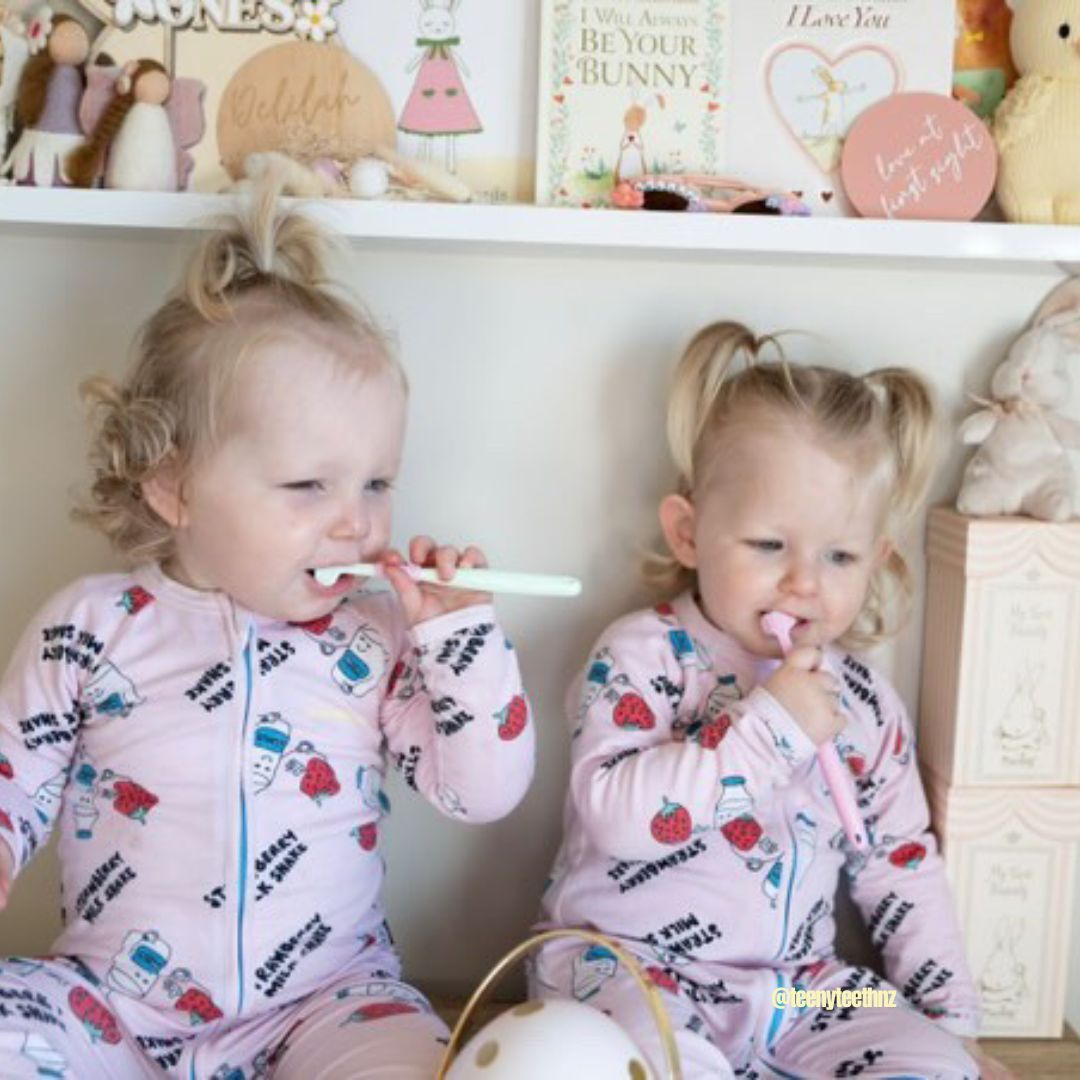 Two kids using colorful Trio Teeth NZ kids toothbrushes for brushing teeth in a bathroom setting.
